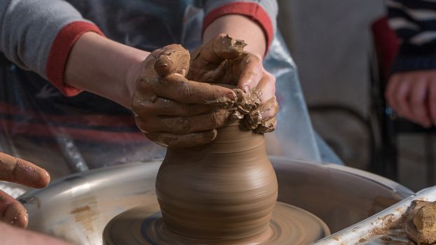 Teaching pottery to children. The teacher gives a master class in modeling