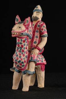 Asian and Oriental painted toy from burnt clay in the form of a man on a horse on a black background