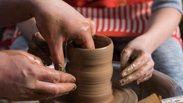 Teaching pottery to children. The teacher gives a master class in modeling