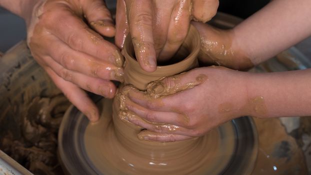 Teaching pottery to children. The teacher gives a master class in modeling