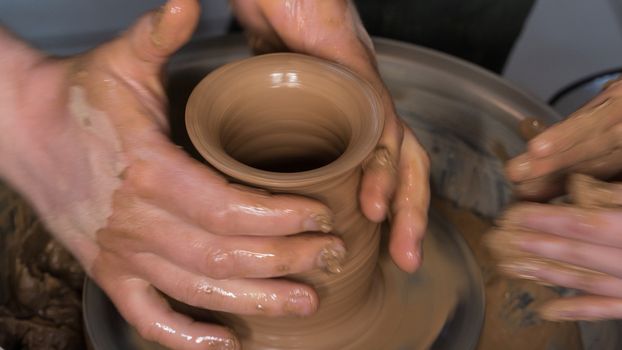 Teaching pottery to children. The teacher gives a master class in modeling