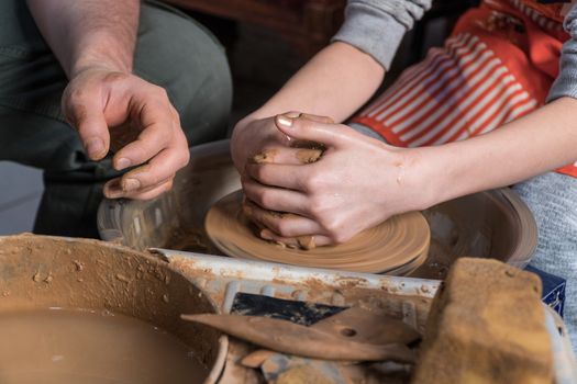 Teaching pottery to children. The teacher gives a master class in modeling