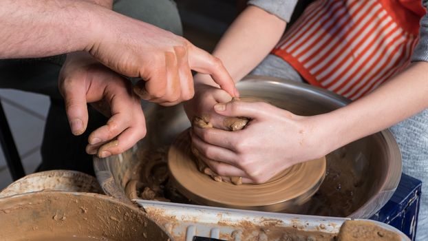 Teaching pottery to children. The teacher gives a master class in modeling