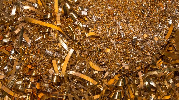 Golden background. Abstract gold background of metal shavings. Wallpaper or screensaver of yellow metallic chips. Processing of ferrous and non-ferrous metals in a factory or plant. Colored shavings. 