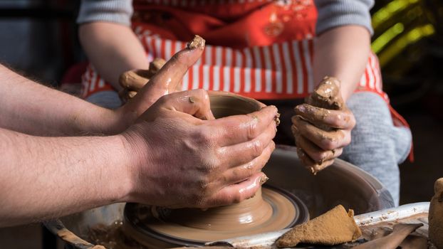 Teaching pottery to children. The teacher gives a master class in modeling