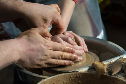 Teaching pottery to children. The teacher gives a master class in modeling