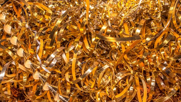 Golden background. Abstract gold background of metal shavings. Wallpaper or screensaver of yellow metallic chips. Processing of ferrous and non-ferrous metals in a factory or plant. Colored shavings. 