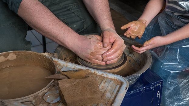 Teaching pottery to children. The teacher gives a master class in modeling