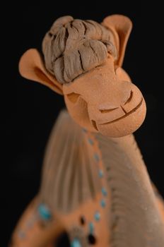 Asian and Oriental painted toy from burnt clay in the form of a camel on a black background