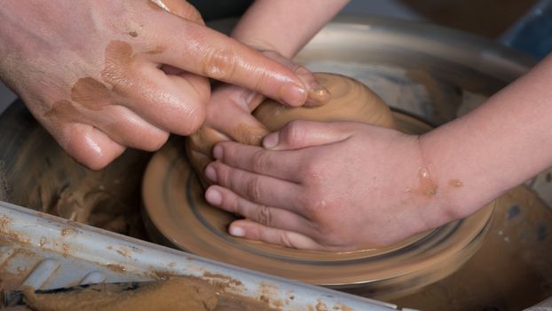 Teaching pottery to children. The teacher gives a master class in modeling