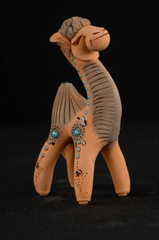 Asian and Oriental painted toy from burnt clay in the form of a camel on a black background