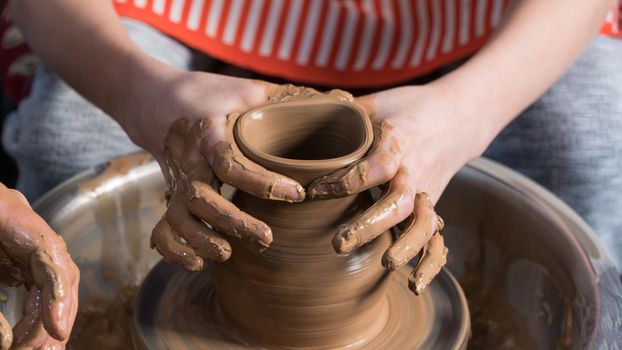 Teaching pottery to children. The teacher gives a master class in modeling