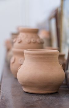 row of clay pots on the shelf, blurred background. children's crafts