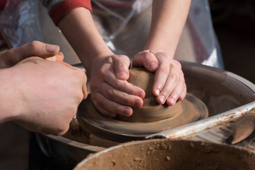 Teaching pottery to children. The teacher gives a master class in modeling