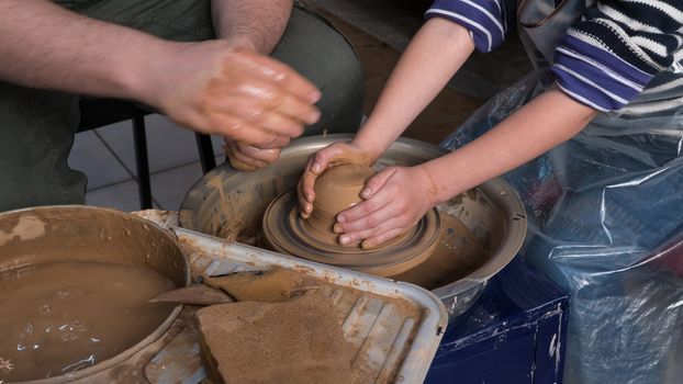 Teaching pottery to children. The teacher gives a master class in modeling