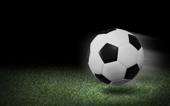 Soccer ball on green grass and black background