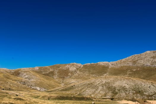 Mountain landscape, karst hill with a lot of stones, grass and blue sky background. Bjelasnica Mountain in autumn, Bosnia and Herzegovina.