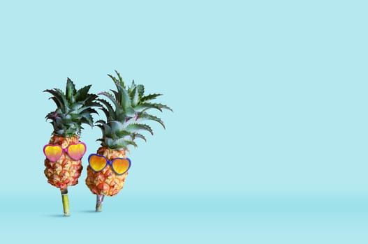 Minimal summer concept design of pineapple wearing sunglasses on blue background