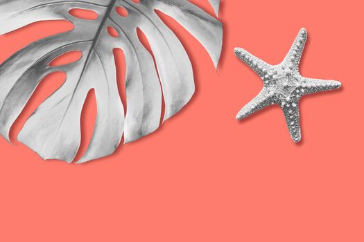 Starfish and monstera tropical leaf on orange background with copy space