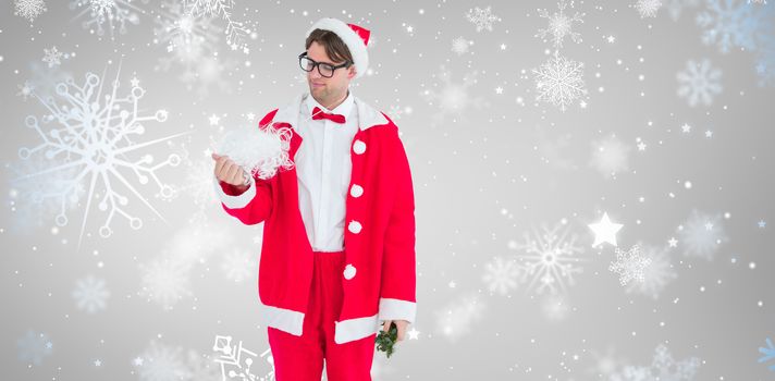 Geeky hipster in santa costume looking at beard  against snowflake pattern