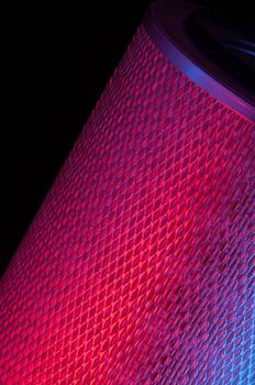 automotive filter cylindrical shape red colors on a black background closeup