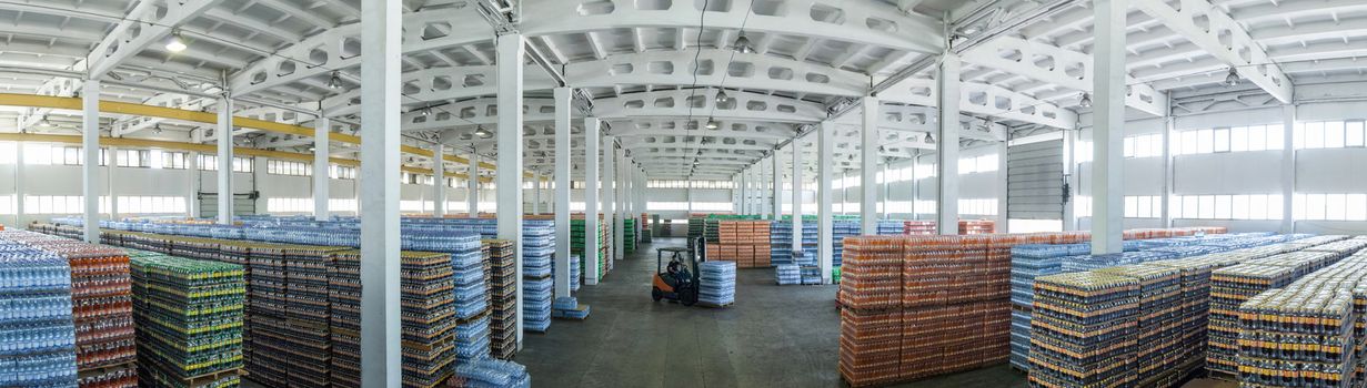 panoramic view of a large warehouse with drinks in plastic bottles with loading machines