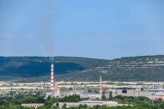 The chimney of the boiler room is smoking. boiler room away in the field.
