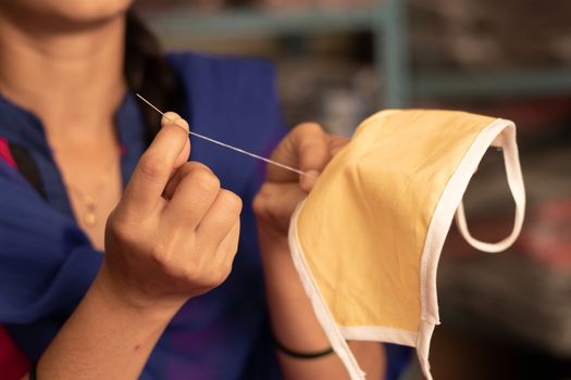 Closeup of Girl hand Knitting DIY face mask at home to protect from covid-19 or coronavirus pandemic at India - Due to shortage of Medical masks woman in India making masks