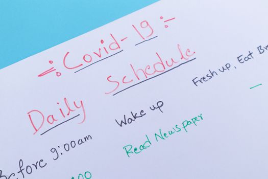 Concept of planning daily schedule during covid-19 or coronavirus lockdown or home quarantine - Close up of Covid-19 daily schedule planner written on white paper.