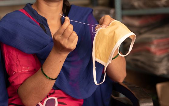 Girl hand Knitting DIY face mask at home to protect from covid-19 or coronavirus pandemic at India - Due to shortage of Medical masks woman in India making masks