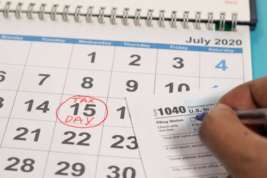 Concept of filling tax form before deadline july 15th with july 15th marked as tax day on calendar as background