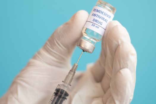 Doctor using syringe to get remdesivir Vaccine for Covid-19 or coronavirus from bottle - Concept of Covid-19 Vaccination, Research, pandemic influenza vaccines around the world