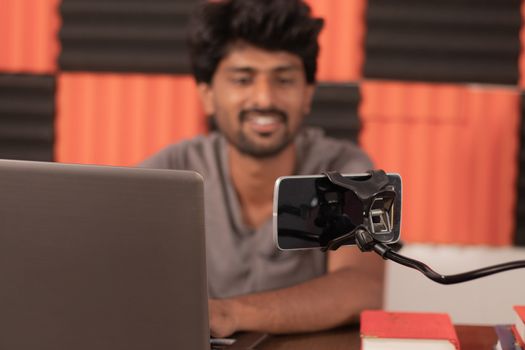 Young man looking on mobile busy in video chat with friends at home during covid-19 or coronavirus pandemic