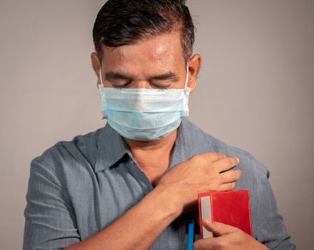 50's man holding bible and praying god with medical face mask wearing to protect from covid-19 or coronavirus pandemic - Concept of hope, peace during tough quarantine times