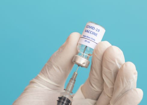 Doctor using syringe to get Covid-19 or coronavirus Vaccine from bottle - Concept of Covid-19 Vaccination, Research, pandemic influenza vaccines around the world