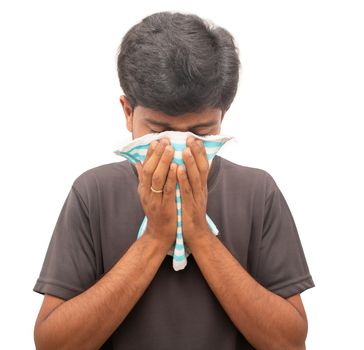 Sick ill health young man sneezing or coughing by covering his face and nose with napkin on isolated background - concept showing of coronavirus or coid 19 advice to cover sneeze and cough with napkin