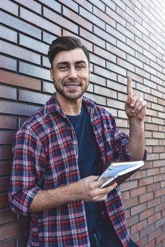 Portrait of smiling handsome man in eyeglasses and shirt isolated on brown brick wall.