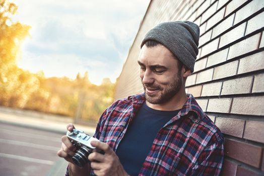 Smiling man with retro photo camera Fashion Travel Lifestyle outdoor while standing against brick wall background