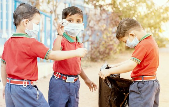 Group of children volunteers picking up, cleaning trash at school - concept of school kids or classmates collecting trash, charity environment