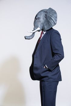A man in a suit and an elephant mask on a light background. Conceptual business background