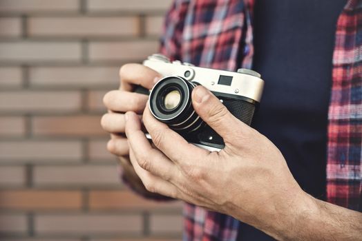 Close up photo man with retro photo camera Fashion Travel Lifestyle outdoor while standing against brick wall background.