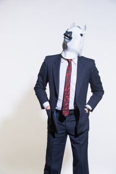 A man in a suit and a horse mask on a light background. Conceptual business background