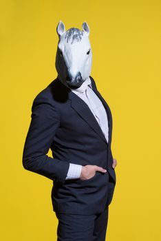 A man in a suit and a horse mask on a yellow background. Conceptual business background