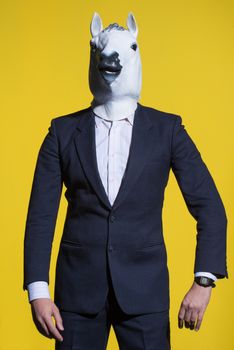 A man in a suit and a horse mask on a yellow background. Conceptual business background