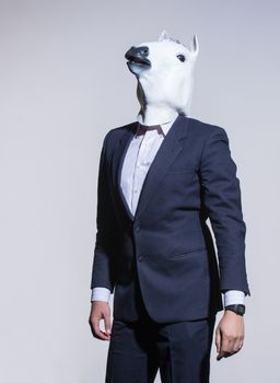 A man in a suit and a horse mask on a light background. Conceptual business background