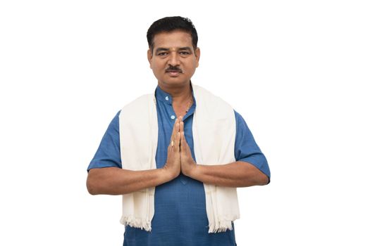 Handsome Indian man in traditional ware showing namaste gesture on isolated background