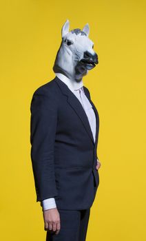 A man in a suit and a horse mask on a yellow background. Conceptual business background