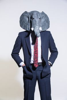 A man in a suit and an elephant mask on a light background. Conceptual business background