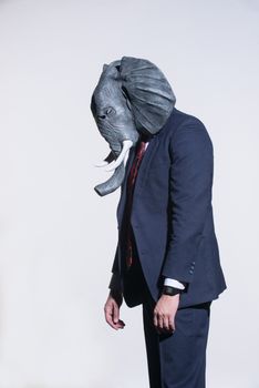 A man in a suit and an elephant mask on a light background. Conceptual business background