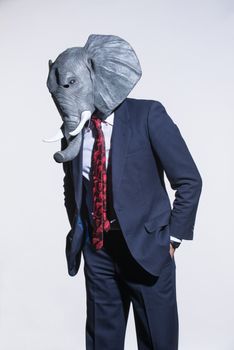 A man in a suit and an elephant mask on a light background. Conceptual business background